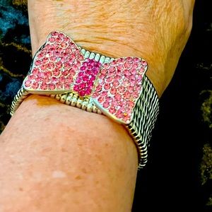 Silver metal stretchy bracelet with pink rhinestone encrusted bow